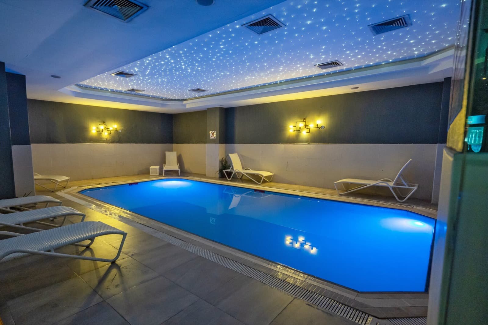 Indoor swimming pool with loungers and a fiber-optic star ceiling at The Green Park Hotel Taksim